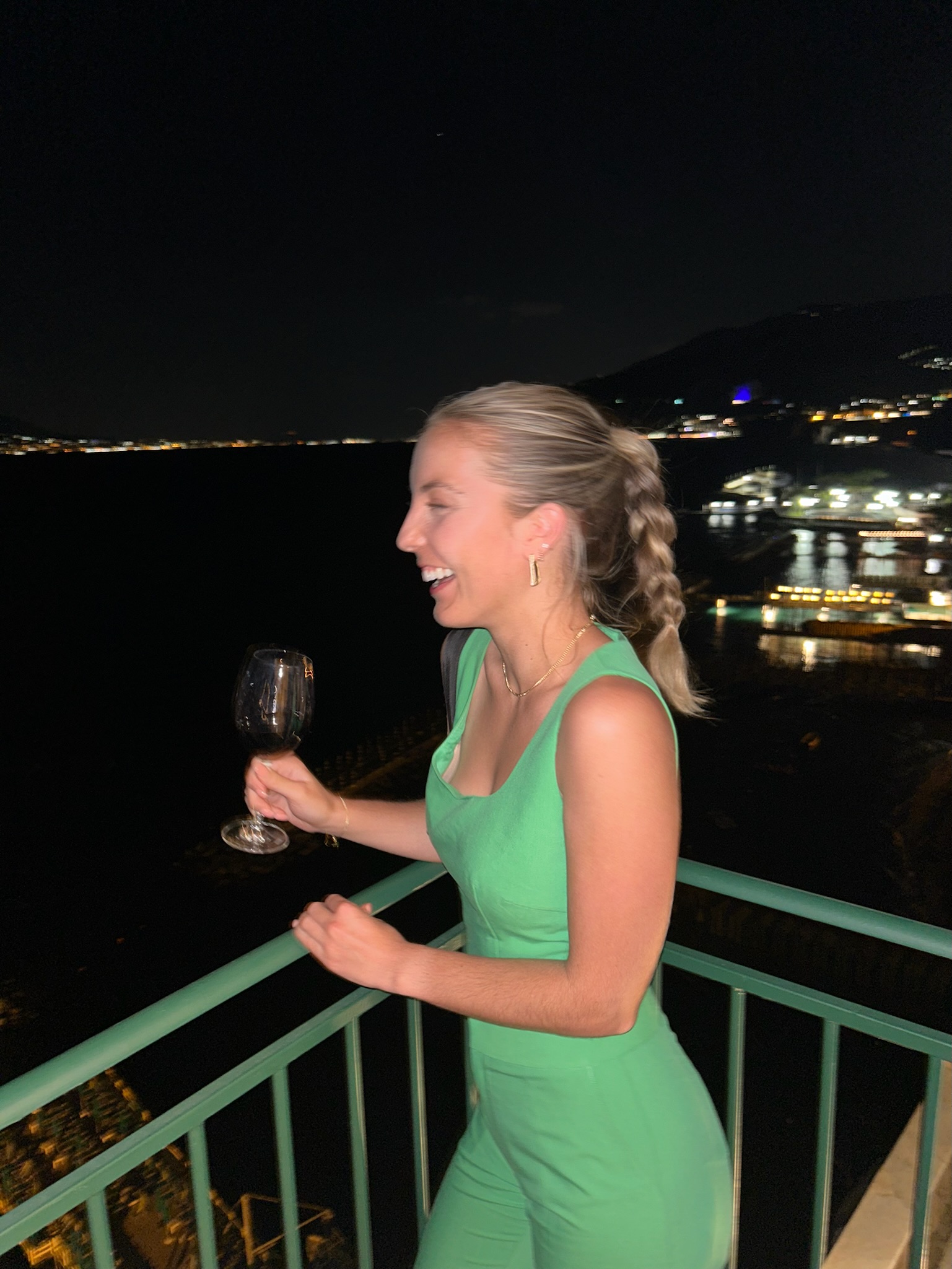 Annie in an elegant green dress enjoying an evening event with city lights in the background
