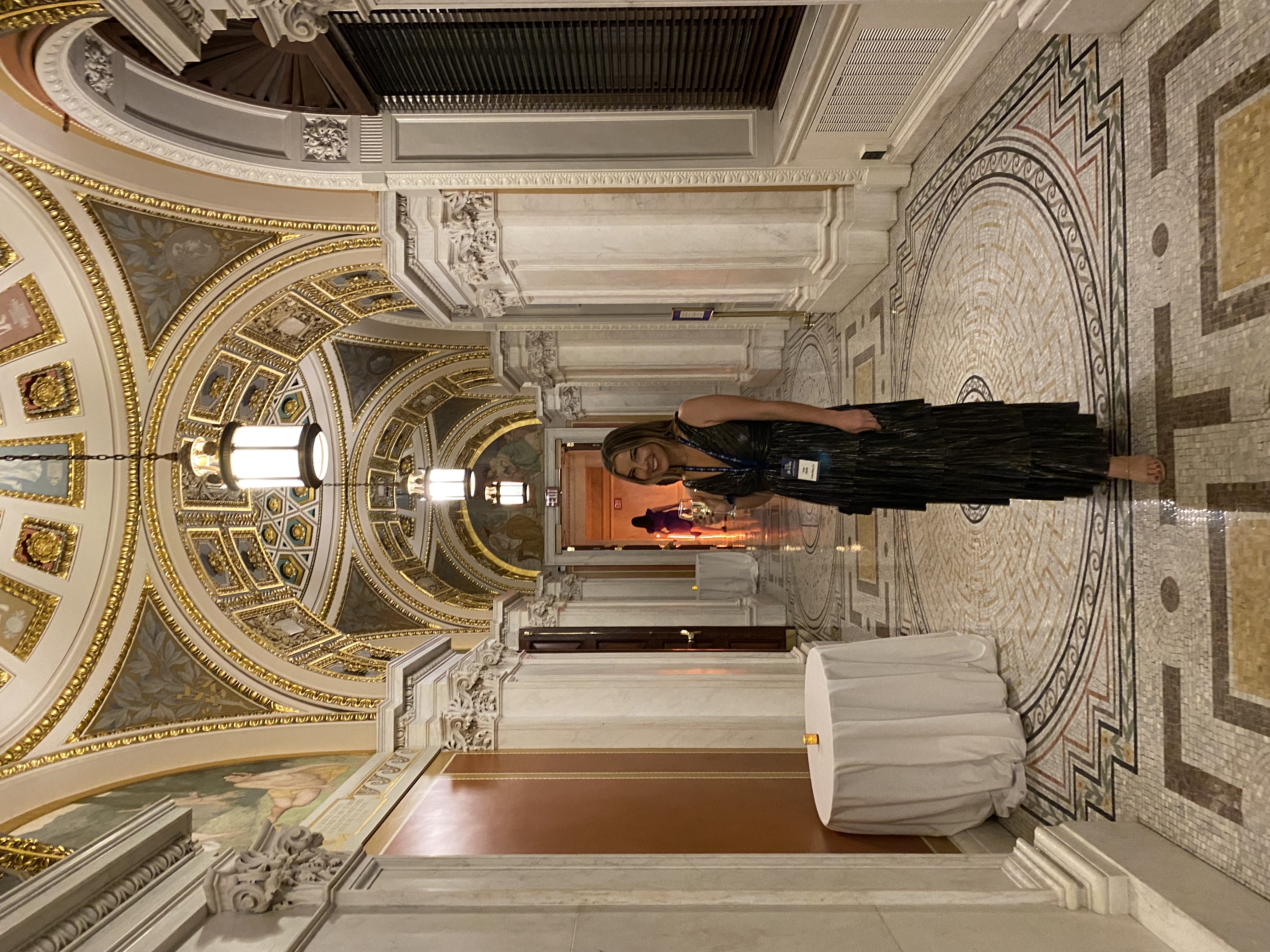 Annie in elegant evening attire at a luxury venue with classical architecture